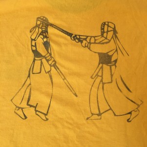 A drawing on the back of a shirt that shows two Kumdo competitors in armor fighting with bamboo swords.